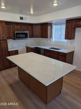 a kitchen with stainless steel appliances a sink a microwave a refrigerator and wooden cabinets