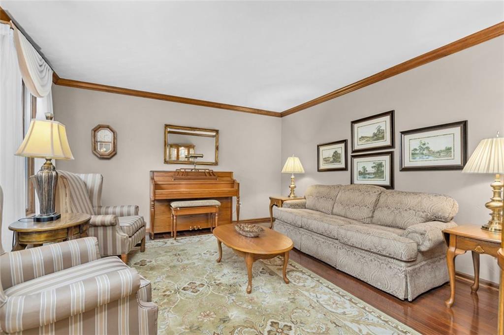The living room has hardwood flooring and is 'dressed with crown molding...