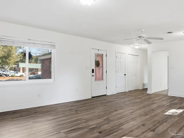 a view of an empty room with wooden floor and a window