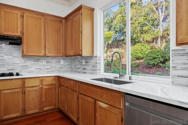 a kitchen with stainless steel appliances wooden cabinets a sink and a window