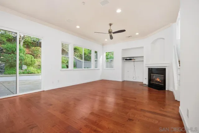 a view of an empty room with a window and kitchen view