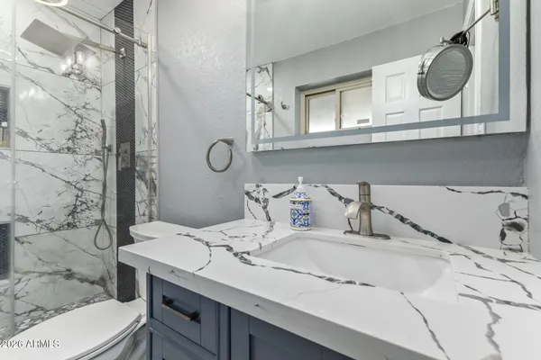 a bathroom with a granite countertop sink a mirror and shower