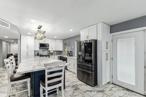 a large kitchen with kitchen island a refrigerator a stove a sink and a dining table with wooden floor