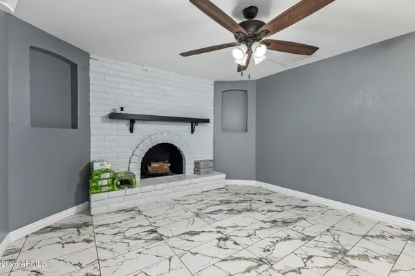 a view of a livingroom with a fireplace chandelier and a ceiling fan