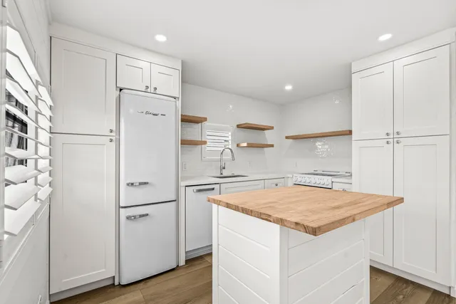 a kitchen with a refrigerator a sink and wooden floor