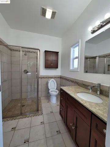a spacious bathroom with a granite countertop sink a toilet a mirror and shower