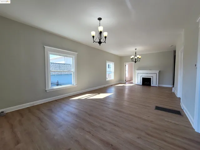 an empty room with wooden floor fireplace and windows