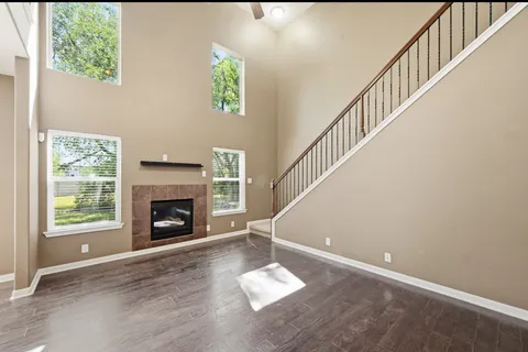 a view of an empty room with wooden floor and a fireplace