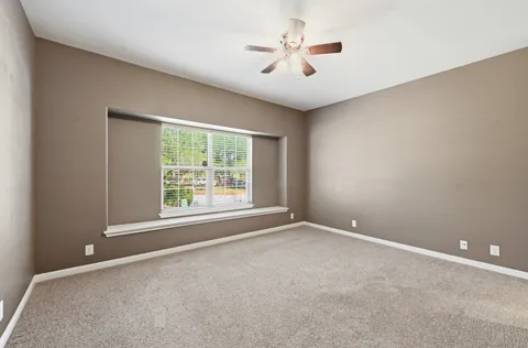 an empty room with a window and a ceiling fan