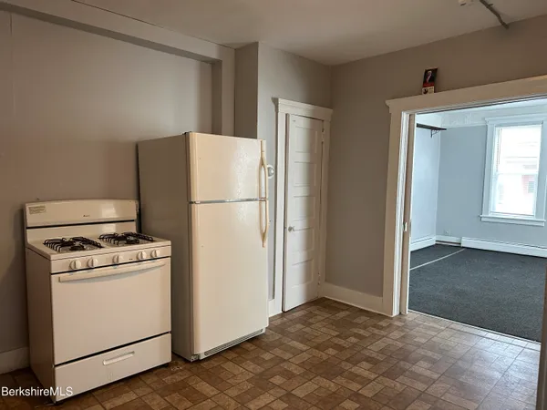 a view of a kitchen with a stove refrigerator and wooden floor