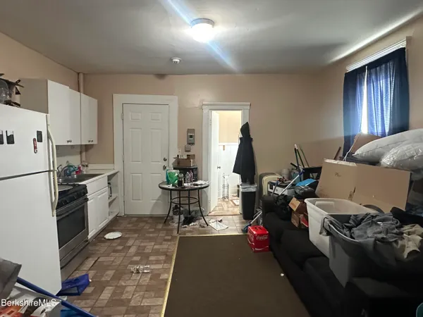 a living room with furniture a flat screen tv and kitchen view