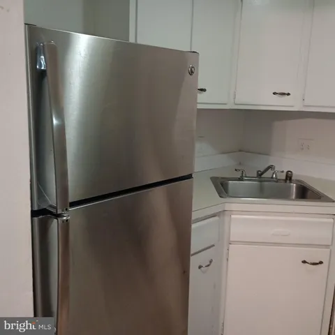 a view of a refrigerator in kitchen and white cabinets