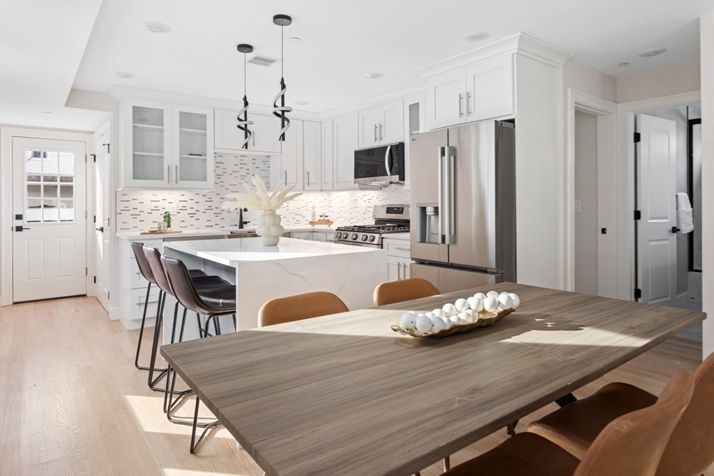 155 A Boston Avenue, Unit 2 Somerville, MA 02144 - Photo 12 of 38 a kitchen with a table chairs refrigerator and cabinets