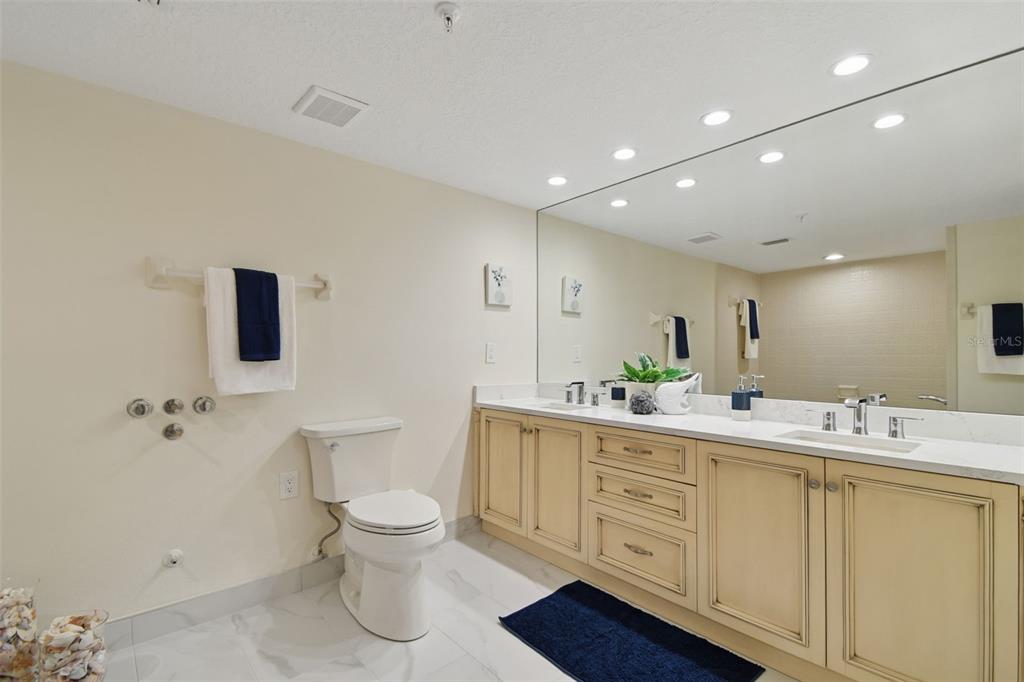 1586 Gulf Boulevard, Unit 2502 Clearwater Beach, FL 33767 - Photo 18 of 47 a bathroom with a double vanity sink toilet and mirror