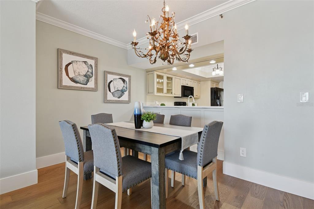 1586 Gulf Boulevard, Unit 2502 Clearwater Beach, FL 33767 - Photo 23 of 47 a view of a dining room with furniture a chandelier and wooden floor