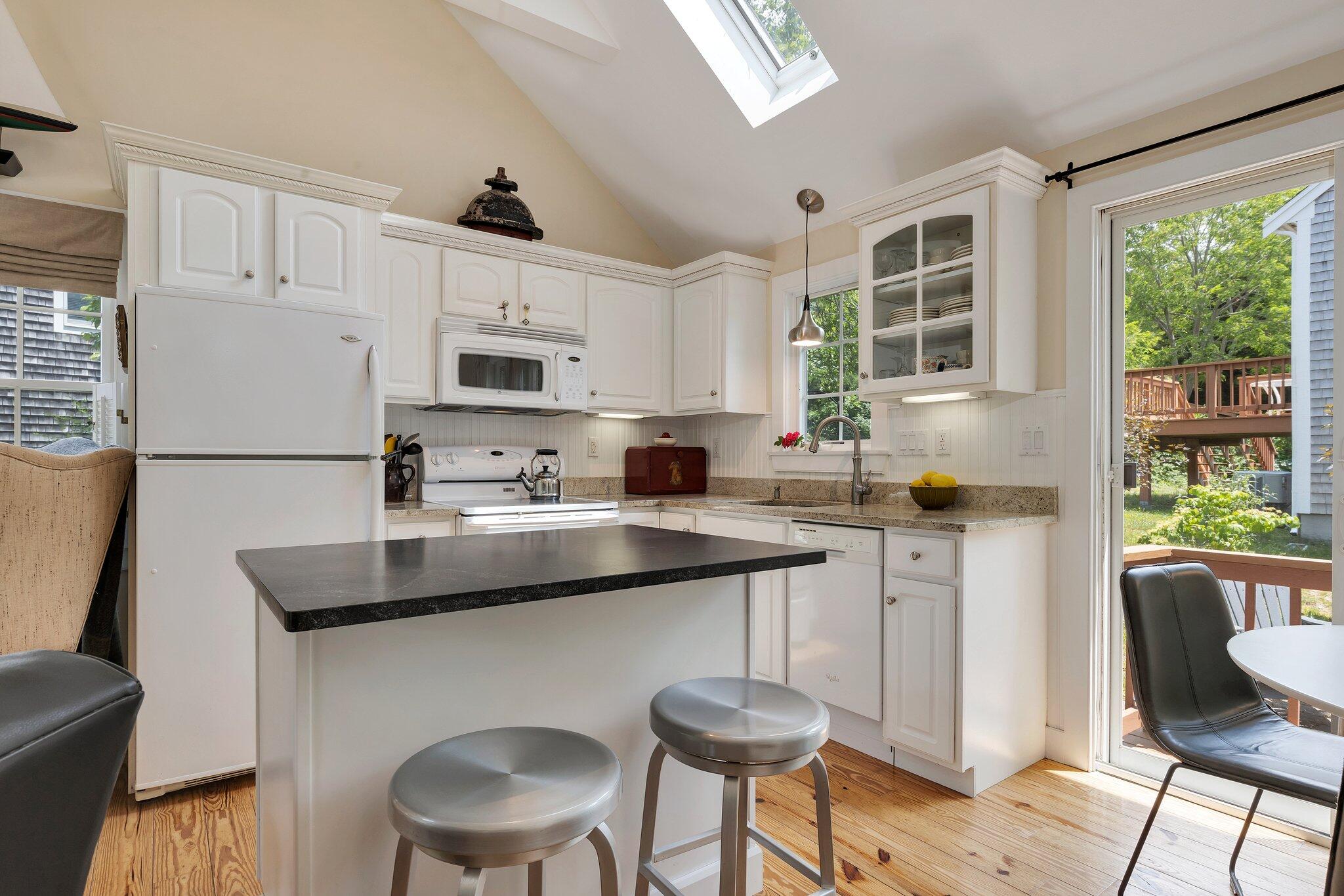 6 Shore Road, Unit 10 Truro, MA 02666 - Photo 8 of 37 a kitchen with stainless steel appliances granite countertop a sink a stove a refrigerator cabinets and a dining table with wooden floor