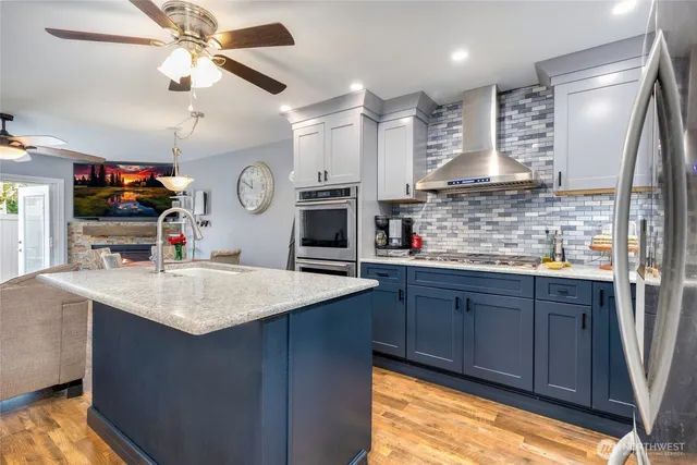 a kitchen with kitchen island granite countertop a sink cabinets and stainless steel appliances