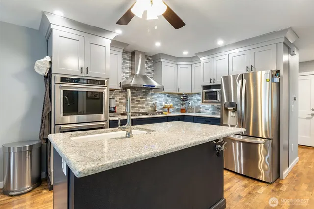 a kitchen with stainless steel appliances granite countertop a sink a stove and a refrigerator