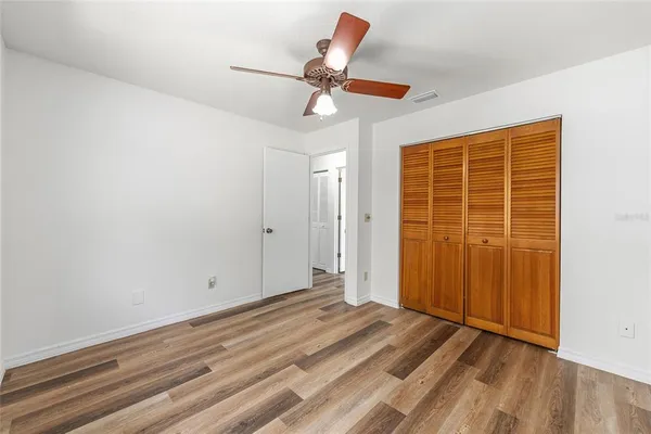 a view of empty room with wooden floor and ceiling fan