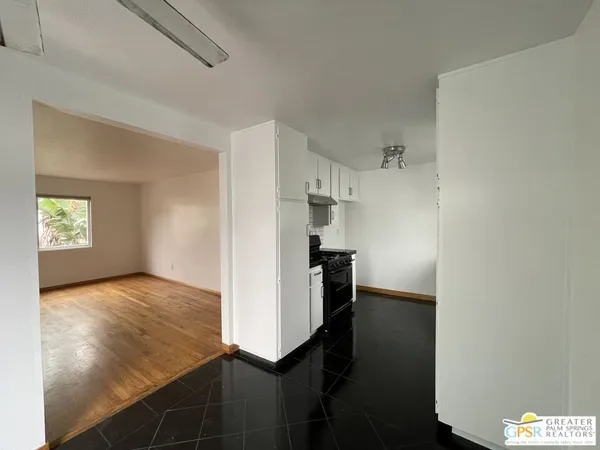 a view of kitchen and empty room with wooden floor