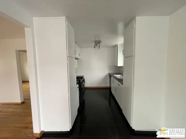 a view of a hallway with wooden floor and a bathroom