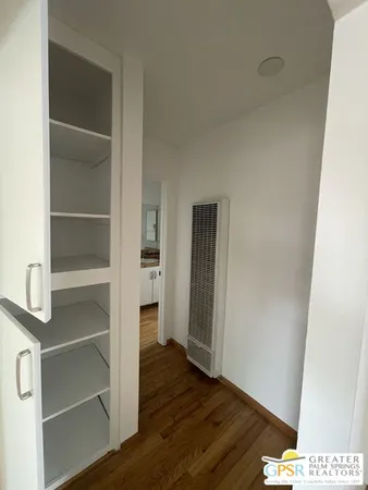 a view of an empty room with wooden floor and closet