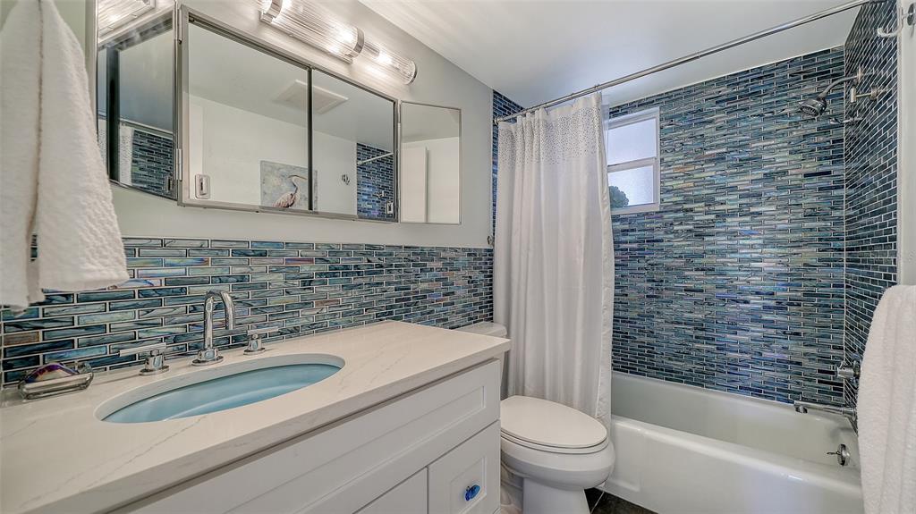4440 Exeter Drive, Unit 301 Longboat Key, FL 34228 - Photo 19 of 72 a bathroom with a sink a toilet a mirror a bathtub and shower