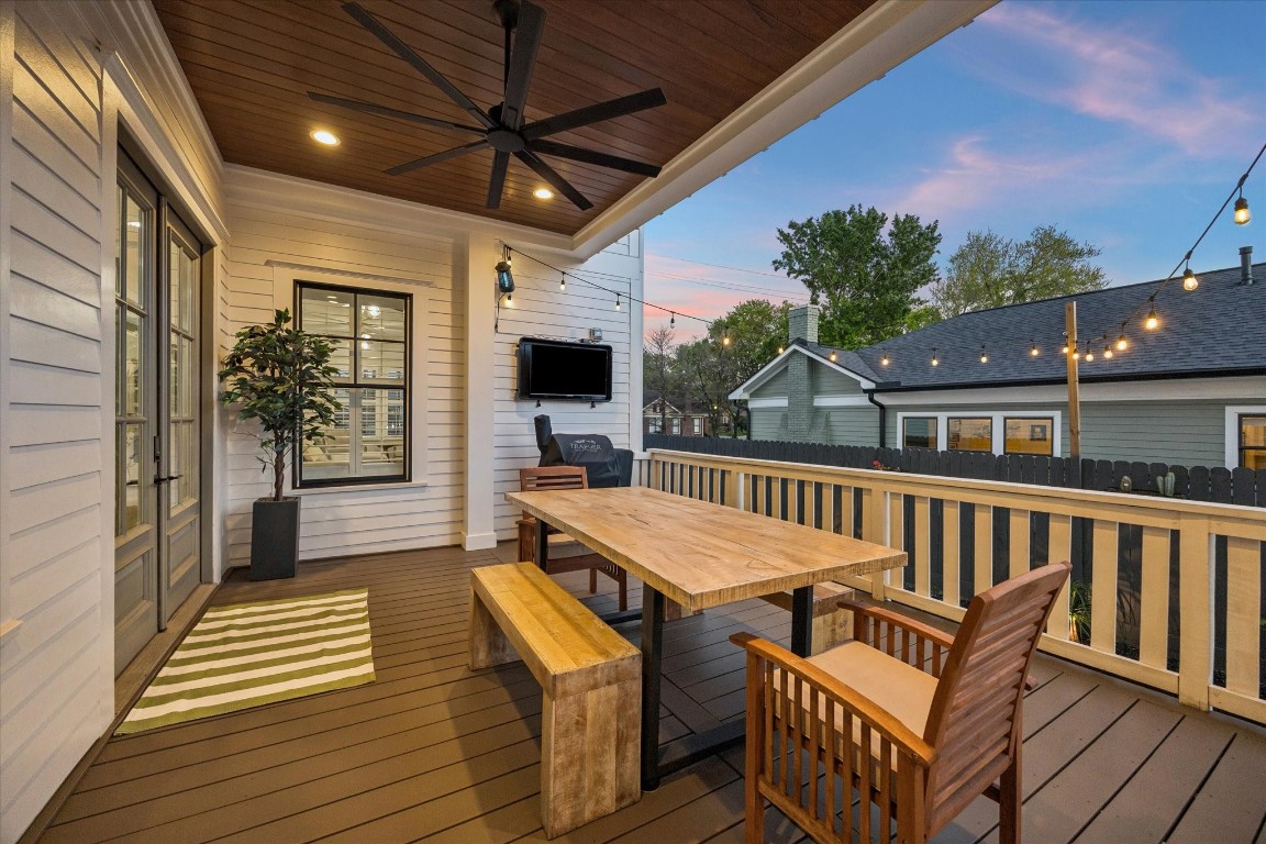 3535 Michaux Street Houston, TX 77009 - Photo 3 of 48 This inviting patio, just off the kitchen, features cozy seating with a wooden table and benches, overhead string lights, a ceiling fan, and an outdoor TV, perfect for entertaining. The covered area offers protection while maintaining an open, airy feel with views of the surrounding neighborhood.