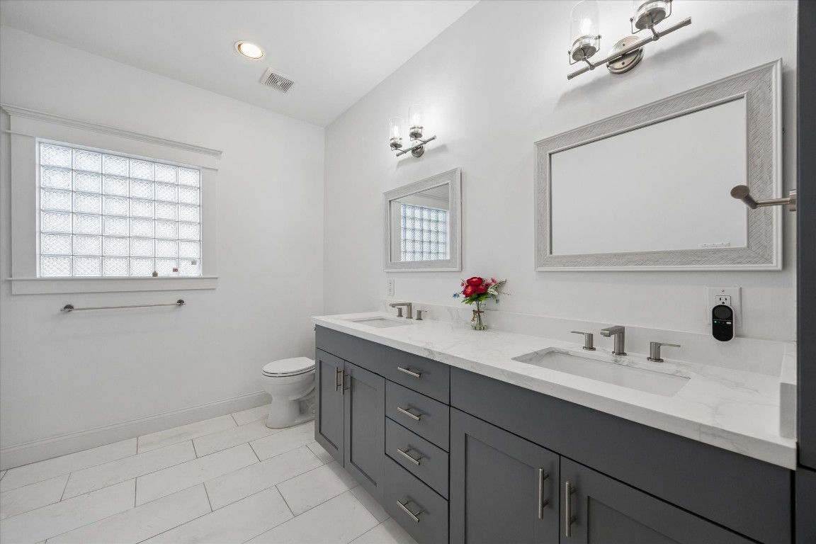 3535 Michaux Street Houston, TX 77009 - Photo 32 of 48 This is a bright, modern bathroom featuring a double vanity with sleek gray cabinets and marble countertops. Accessible from the hall it is convenient to the upstairs family area, as well as the two back bedrooms. The frosted glass window allows consistent natural light without sacrificing privacy.