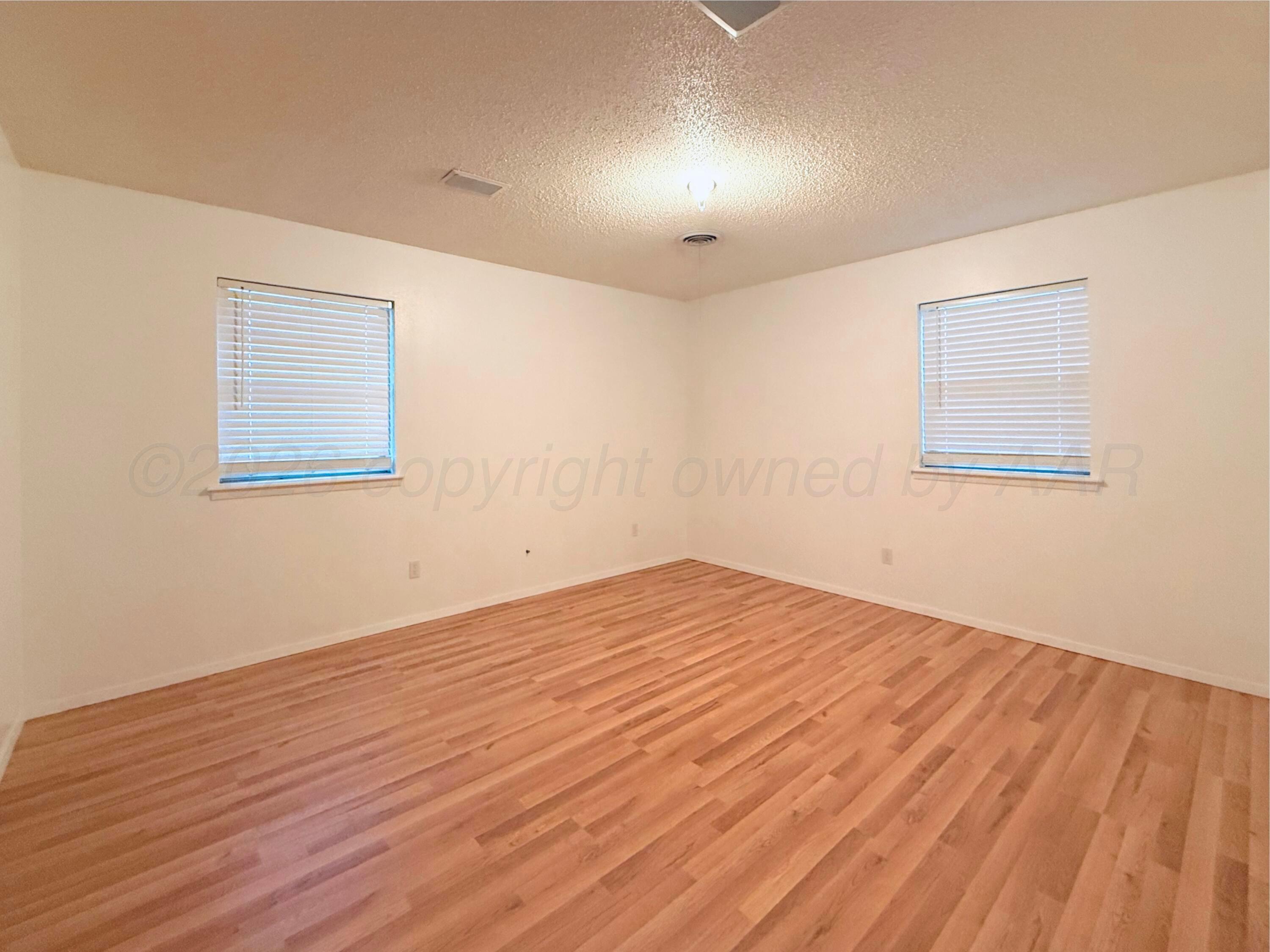 1713 Sunset Avenue Dumas, TX 79029 - Photo 11 of 15 a view of an empty room with wooden floor and a window