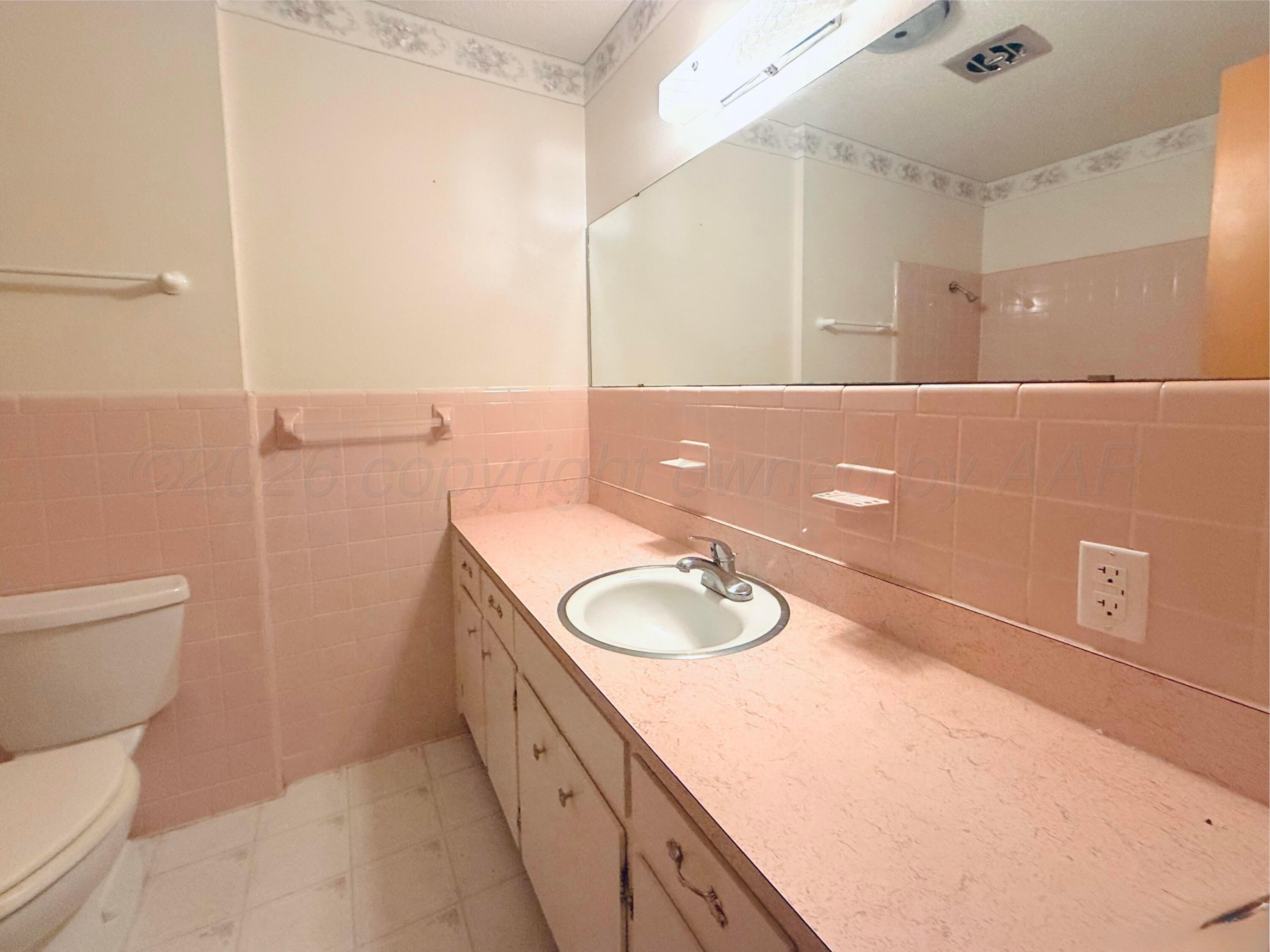 1713 Sunset Avenue Dumas, TX 79029 - Photo 9 of 15 a bathroom with a granite countertop sink a toilet and a mirror