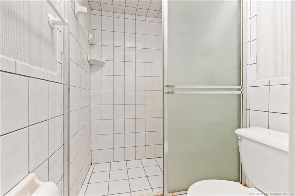 2493 Southwest Murphy Road Palm City, FL 34990 - Photo 29 of 50 a white toilet sitting next to a shower curtain