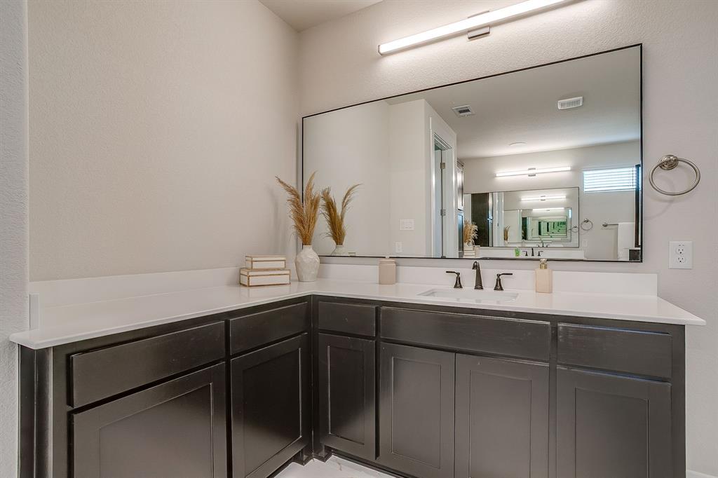 4511 Matador Rnch Road Waxahachie, TX 75165 - Photo 19 of 36 L-shaped vanity with dark wood-finish cabinetry, white countertop, rectangular undermount sink, and matte black faucet