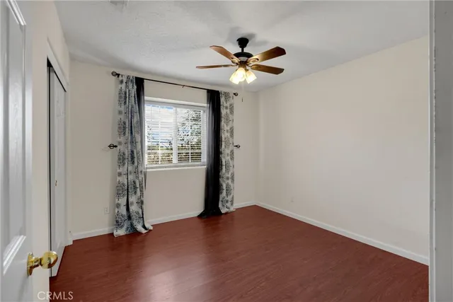 an empty room with wooden floor and ceiling fan