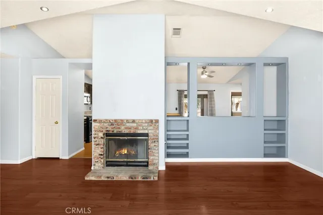 a kitchen with stainless steel appliances granite countertop a stove top oven a sink dishwasher a refrigerator and a microwave oven with wooden floor