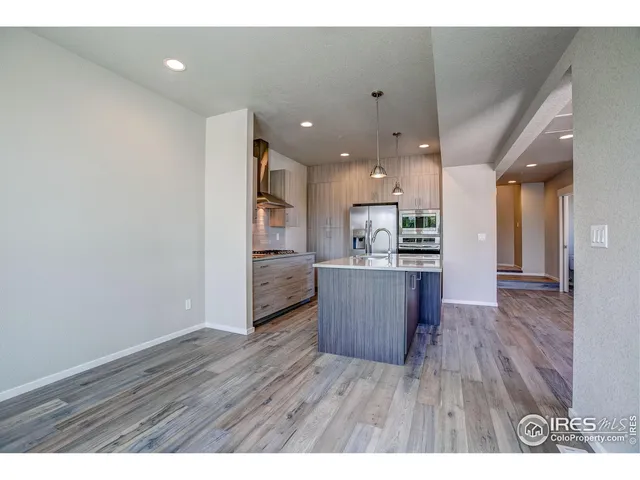 a room with stainless steel appliances kitchen island wooden floors and view living room
