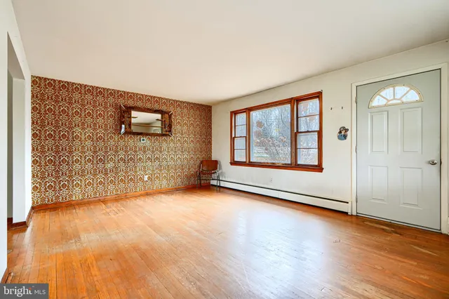 a view of an empty room with glass door and wooden floor