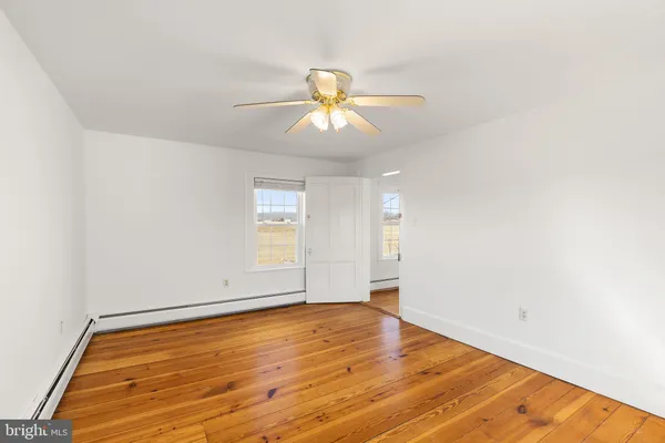 a view of empty room with wooden floor and fan