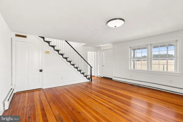 a view of an empty room with wooden floor and stairs