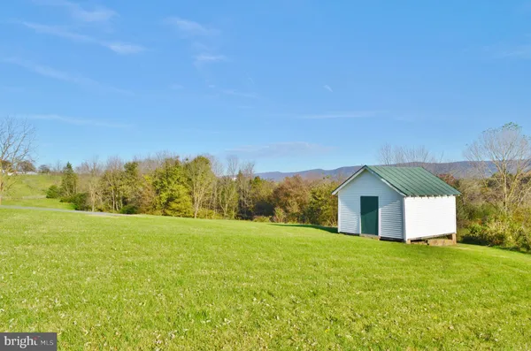 a front view of a house with a yard and mountain view in back