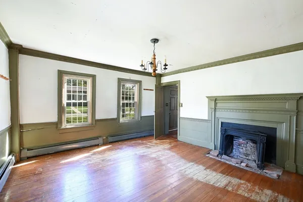 a view of an empty room with wooden floor fireplace and a window