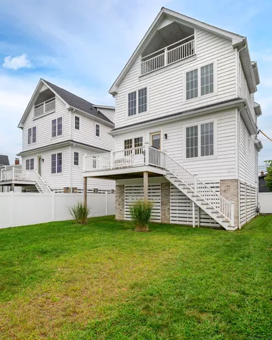 a white house that has a small yard and trees in the background