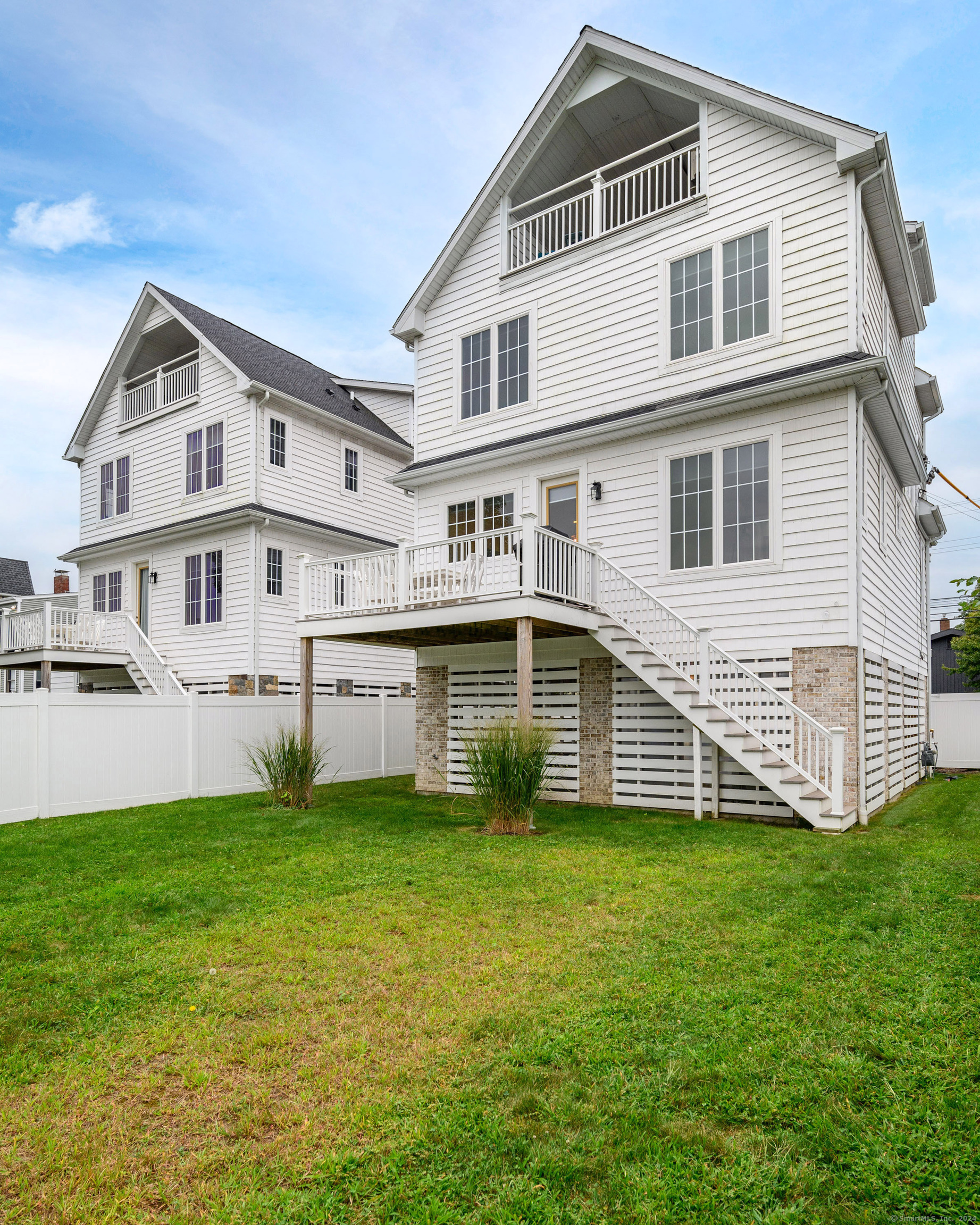 1033 Reef Road Fairfield, CT 06824 - Photo 28 of 32 a white house that has a small yard and trees in the background