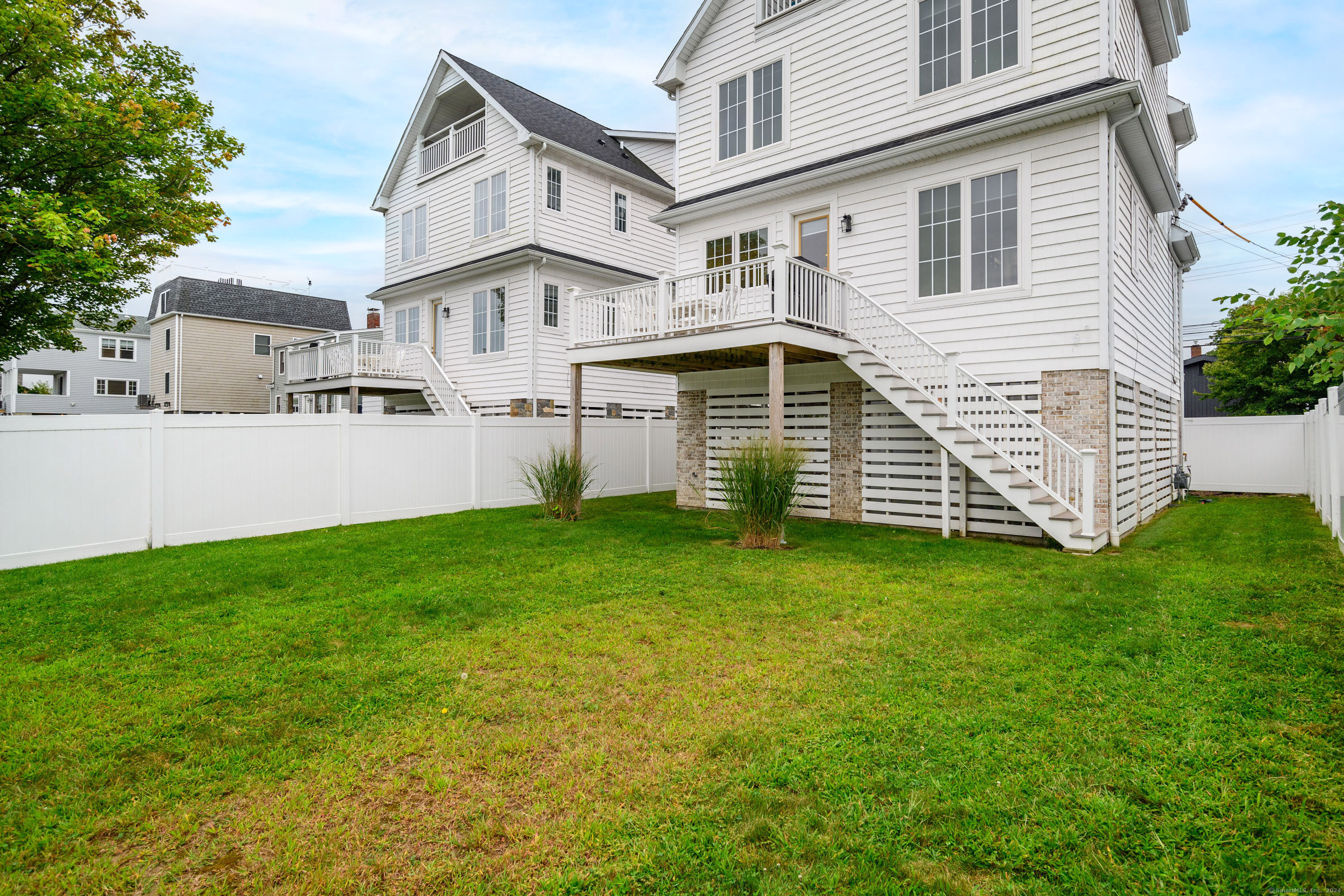1033 Reef Road Fairfield, CT 06824 - Photo 29 of 32 a white house that has a small yard and a wooden fence