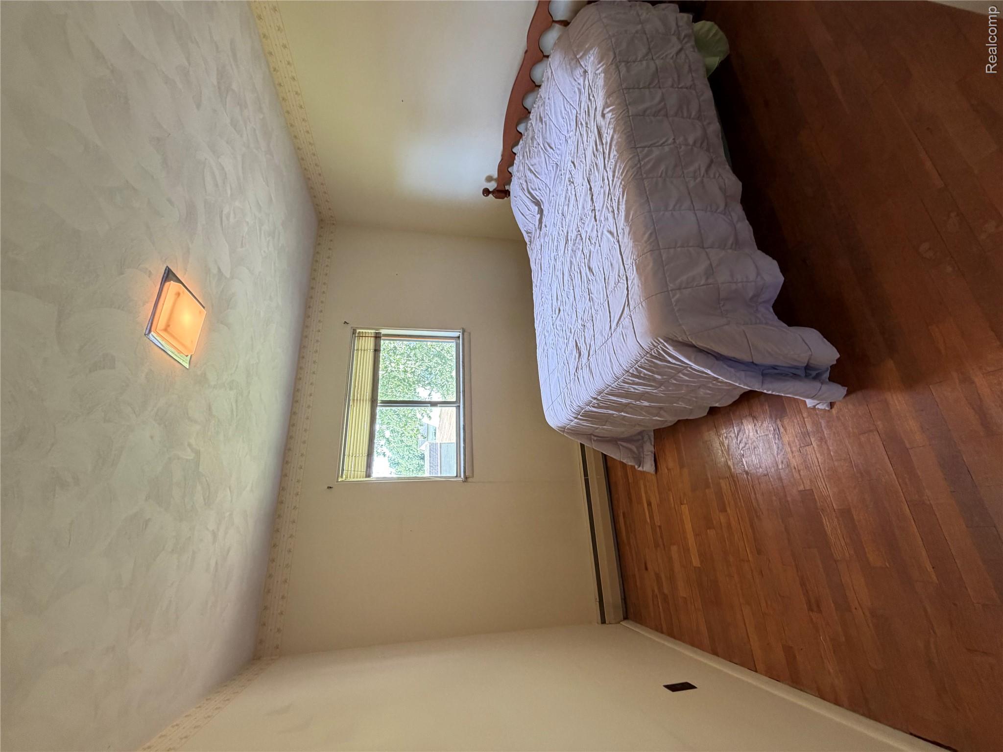 8886 East Burnside Road Brown City, MI 48416 - Photo 21 of 22 Hardwood flooring throughout featuring baseboard trim, a window with blinds, and a flush-mount ceiling light fixture