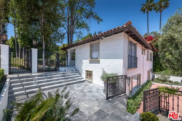 a view of a house with a small yard plants and large tree