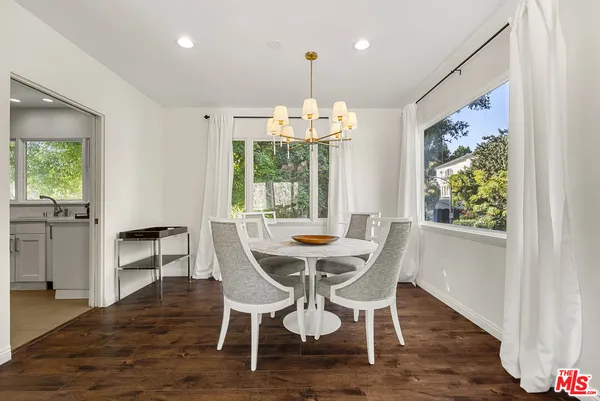 a dining room with wooden floor a chandelier a wooden table and chairs