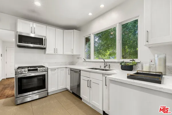 a kitchen with stainless steel appliances granite countertop white cabinets and a stove top oven