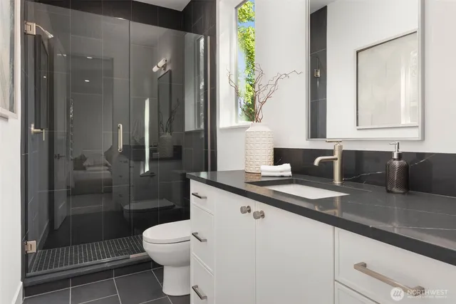 a bathroom with a granite countertop sink a toilet a shower and a mirror