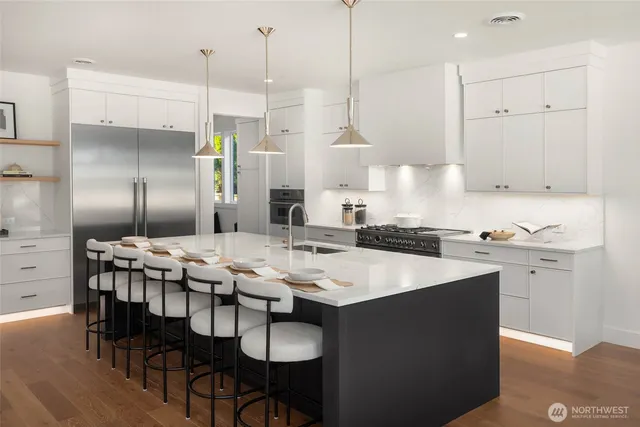a kitchen with stainless steel appliances kitchen island granite countertop a table chairs in it and white cabinets